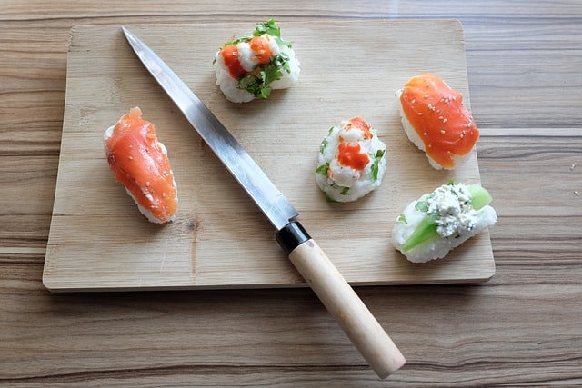 Holzbrett mit Sushi Messer und Sushi Rollen
