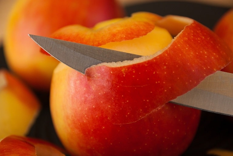 Ein Apfel wird mit einem Obstmesser geschält.